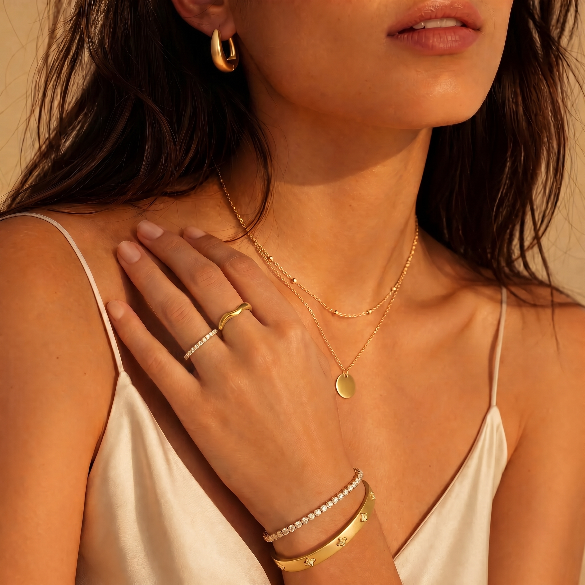 Gold jewelry stack worn at the collarbone — Livia pave ring, Alessia band, Bianca tennis bracelet and Stella bangle, Serena layered disc necklace
